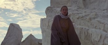 Movie still from “Orca” (1977), directed by Michael Anderson – A woman standing in front of a stone wall; Medium shot, Low angle