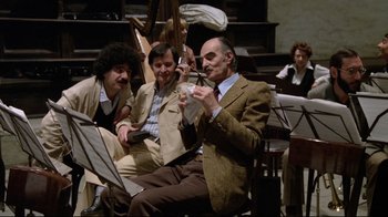Movie still from “Orchestra Rehearsal” (1978), directed by Federico Fellini – A group of people sitting in a room with musical instruments; Wide shot, High angle