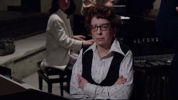 Movie still from “Orchestra Rehearsal” (1978), directed by Federico Fellini – An older woman sitting in front of a group of people; Close Up shot, Over the shoulder angle