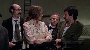 Movie still from “Orchestra Rehearsal” (1978), directed by Federico Fellini – A group of people standing next to each other in a room; Medium shot, Over the shoulder angle