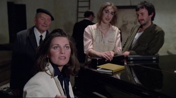 Movie still from “Orchestra Rehearsal” (1978), directed by Federico Fellini – A woman sitting at a piano in front of a group of people; Medium shot, Over the shoulder angle