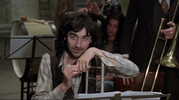 Movie still from “Orchestra Rehearsal” (1978), directed by Federico Fellini – A man with long hair and a beard sitting in a chair; Medium shot, High angle