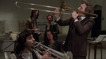 Movie still from “Orchestra Rehearsal” (1978), directed by Federico Fellini – A group of men playing musical instruments in a room; Medium shot, Low angle