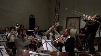 Movie still from “Orchestra Rehearsal” (1978), directed by Federico Fellini – A group of men playing musical instruments in a room; Wide shot, Low angle