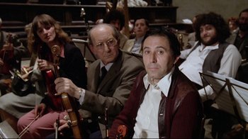 Movie still from “Orchestra Rehearsal” (1978), directed by Federico Fellini – Two men are sitting in a room and one of them is holding a violin; Medium shot, Low angle
