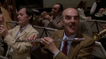 Movie still from “Orchestra Rehearsal” (1978), directed by Federico Fellini – A group of men sitting in a room playing musical instruments; Close Up shot, Low angle