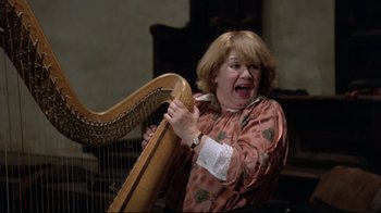 Movie still from “Orchestra Rehearsal” (1978), directed by Federico Fellini – A woman is holding a harp in her hands; Medium shot, Low angle