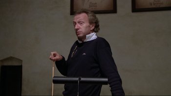Movie still from “Orchestra Rehearsal” (1978), directed by Federico Fellini – A man standing in front of a microphone holding a wooden stick; Medium shot, Low angle