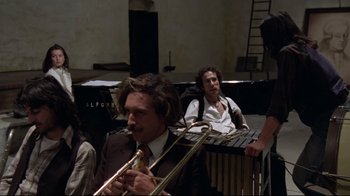 Movie still from “Orchestra Rehearsal” (1978), directed by Federico Fellini – A man in a brown suit playing a musical instrument; Medium shot, High angle