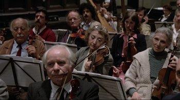 Movie still from “Orchestra Rehearsal” (1978), directed by Federico Fellini – A group of people sitting in a room playing musical instruments; Medium shot, High angle