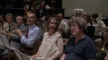 Movie still from “Orchestra Rehearsal” (1978), directed by Federico Fellini – A group of people sitting in a room with musical instruments; Medium shot, Over the shoulder angle