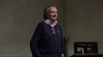 Movie still from “Orchestra Rehearsal” (1978), directed by Federico Fellini – A man standing in front of an audience wearing a sweater; Medium shot, Low angle