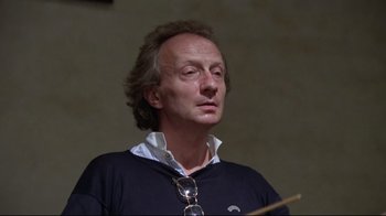 Movie still from “Orchestra Rehearsal” (1978), directed by Federico Fellini – A person wearing glasses and a sweater; Close Up shot, Low angle