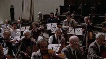 Movie still from “Orchestra Rehearsal” (1978), directed by Federico Fellini – A group of people playing instruments in a room; Wide shot, High angle