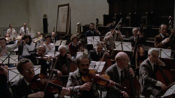 Movie still from “Orchestra Rehearsal” (1978), directed by Federico Fellini – A large group of men playing musical instruments in a room; Extreme Wide shot, High angle
