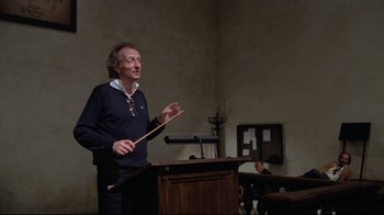 Movie still from “Orchestra Rehearsal” (1978), directed by Federico Fellini – A man standing in front of a podium holding a stick; Medium shot, Low angle