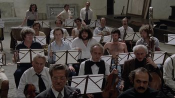 Movie still from “Orchestra Rehearsal” (1978), directed by Federico Fellini – A large group of people sitting in a room; Wide shot, High angle