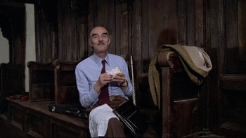 Movie still from “Orchestra Rehearsal” (1978), directed by Federico Fellini – A man sitting on top of a wooden bench; Medium shot, Low angle