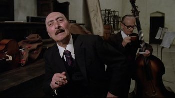 Movie still from “Orchestra Rehearsal” (1978), directed by Federico Fellini – A man in a black suit and a man in a purple tie; Medium shot, Low angle