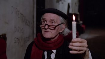 Movie still from “Orchestra Rehearsal” (1978), directed by Federico Fellini – An older man holding a candle in a dark room; Close Up shot, Low angle