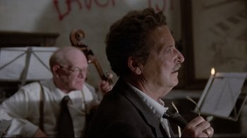 Movie still from “Orchestra Rehearsal” (1978), directed by Federico Fellini – A man in a suit and tie next to another man in a suit and tie; Close Up shot, Low angle