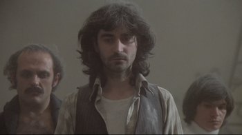 Movie still from “Orchestra Rehearsal” (1978), directed by Federico Fellini – A man with long black hair wearing a vest; Medium shot, Low angle
