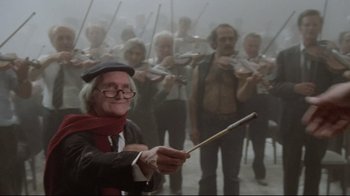 Movie still from “Orchestra Rehearsal” (1978), directed by Federico Fellini – An old man holding a stick in front of a group of people; Medium shot, Low angle