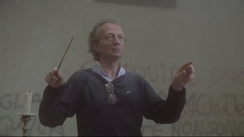 Movie still from “Orchestra Rehearsal” (1978), directed by Federico Fellini – An older man is holding a wooden stick and wearing glasses; Close Up shot, Low angle