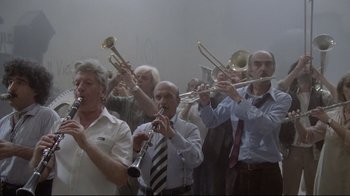 Movie still from “Orchestra Rehearsal” (1978), directed by Federico Fellini – A group of men in dress clothes playing musical instruments; Wide shot, Low angle