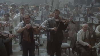 Movie still from “Orchestra Rehearsal” (1978), directed by Federico Fellini – A group of men playing musical instruments in a room; Wide shot, Low angle