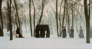Movie still from “Orlando” (1992), directed by Sally Potter – A group of people standing in the middle of a snow covered forest; Wide shot, High angle