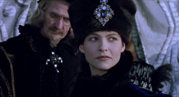 Movie still from “Orlando” (1992), directed by Sally Potter – A woman wearing a fur hat with a cross on top of her head; Close Up shot, Over the shoulder angle