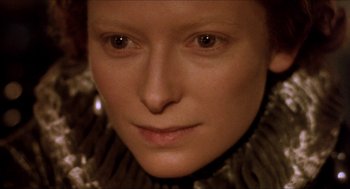 Movie still from “Orlando” (1992), directed by Sally Potter – A woman's face in a black and gold outfit; Close Up shot, Overhead angle