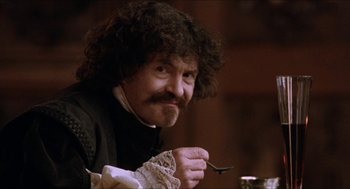 Movie still from “Orlando” (1992), directed by Sally Potter – A man with curly hair and a mustache holding a spoon; Close Up shot, Low angle