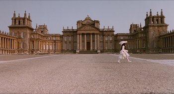 Movie still from “Orlando” (1992), directed by Sally Potter – A person walking in front of a large building with an umbrella; Extreme Wide shot, Low angle