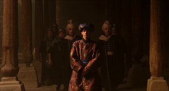 Movie still from “Orlando” (1992), directed by Sally Potter – A group of men standing next to each other in a dark room; Wide shot, Low angle