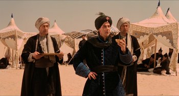 Movie still from “Orlando” (1992), directed by Sally Potter – A man wearing a turban is looking at his cell phone; Medium shot, Over the shoulder angle