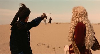 Movie still from “Orlando” (1992), directed by Sally Potter – A man holding a camera up in the desert; Wide shot, Over the shoulder angle