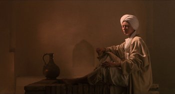 Movie still from “Orlando” (1992), directed by Sally Potter – A man sitting on a bench next to an urn; Wide shot, Low angle