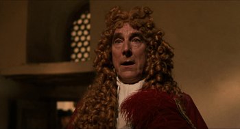 Movie still from “Orlando” (1992), directed by Sally Potter – An old man with a long curly hair and a red wig; Close Up shot, Over the shoulder angle