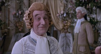 Movie still from “Orlando” (1992), directed by Sally Potter – A man in a wig and a white shirt is smiling for the camera; Close Up shot, Over the shoulder angle