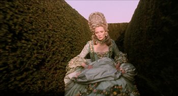 Movie still from “Orlando” (1992), directed by Sally Potter – A woman dressed in period costume sitting in a hedge; Medium shot, Overhead angle