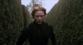 Movie still from “Orlando” (1992), directed by Sally Potter – A woman in a black dress standing in the middle of a forest; Medium shot, Overhead angle