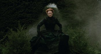 Movie still from “Orlando” (1992), directed by Sally Potter – A woman dressed in black sitting in the middle of a forest; Wide shot, Low angle