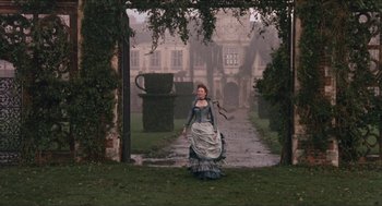Movie still from “Orlando” (1992), directed by Sally Potter – A woman dressed in period clothing walking through a garden; Extreme Wide shot, High angle