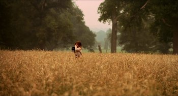 Movie still from “Orlando” (1992), directed by Sally Potter – A woman in a field taking a picture with a camera; Extreme Wide shot, Over the shoulder angle