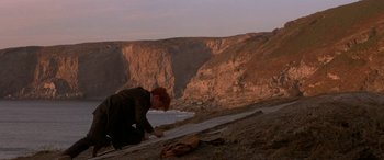 Movie still from “Oscar and Lucinda” (1997), directed by Gillian Armstrong – A man is painting on the side of a cliff; Wide shot, High angle