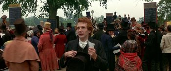 Movie still from “Oscar and Lucinda” (1997), directed by Gillian Armstrong – A man with red hair in a crowd of people; Medium shot, Over the shoulder angle