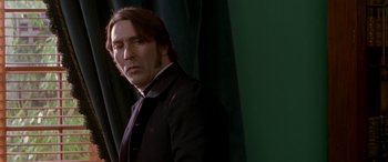 Movie still from “Oscar and Lucinda” (1997), directed by Gillian Armstrong – A man with long hair wearing a suit and tie; Close Up shot, Low angle