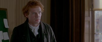 Movie still from “Oscar and Lucinda” (1997), directed by Gillian Armstrong – A man with red hair wearing a black jacket; Close Up shot, Over the shoulder angle